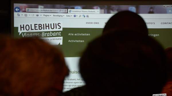 Enkele silhouetten van personen bedekken een projectie van de website van het Holebihuis