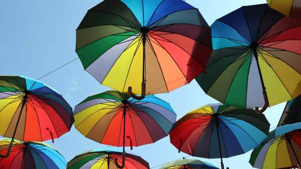 Enkele regenboogparaplu's die in de blauwe lucht lijken te zweven