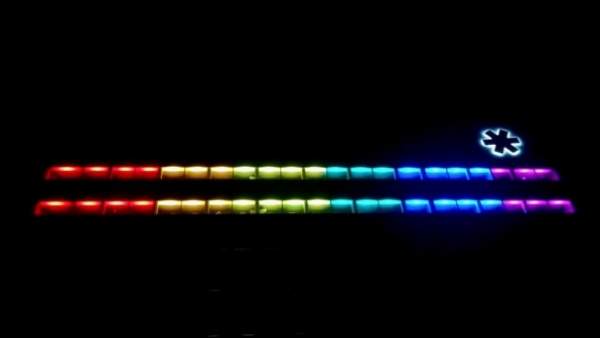 Een donkere foto van de ramen van de twee bovenste verdiepingen van het Provinciehuis van Vlaams-Brabant langs de buitenkant, de ramen zijn belicht met regenboogkleuren. Link bovenaan schijnt een wit ligt achter het logo van Vlaams-Brabant.